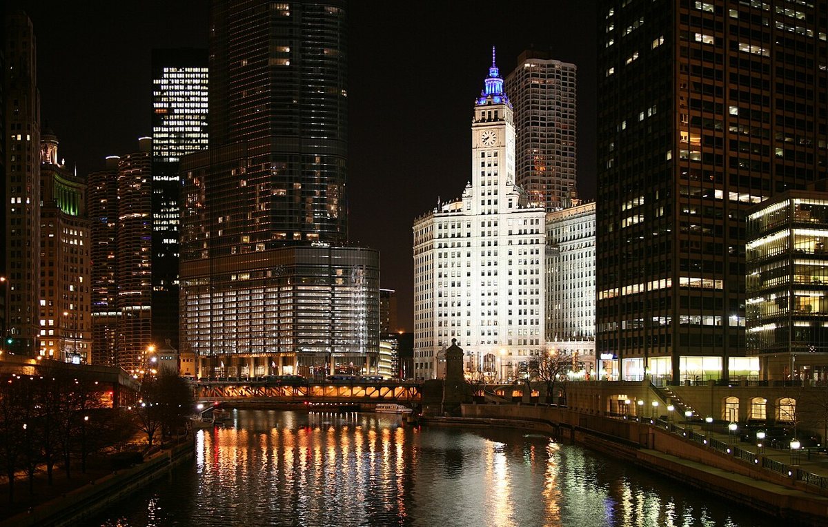 Couple walking the Chicago Riverwalk at dusk with the skyline reflected in the water
