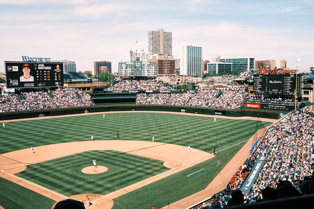 A day game at Wrigley Field with the outfield ivy and hand-operated scoreboard